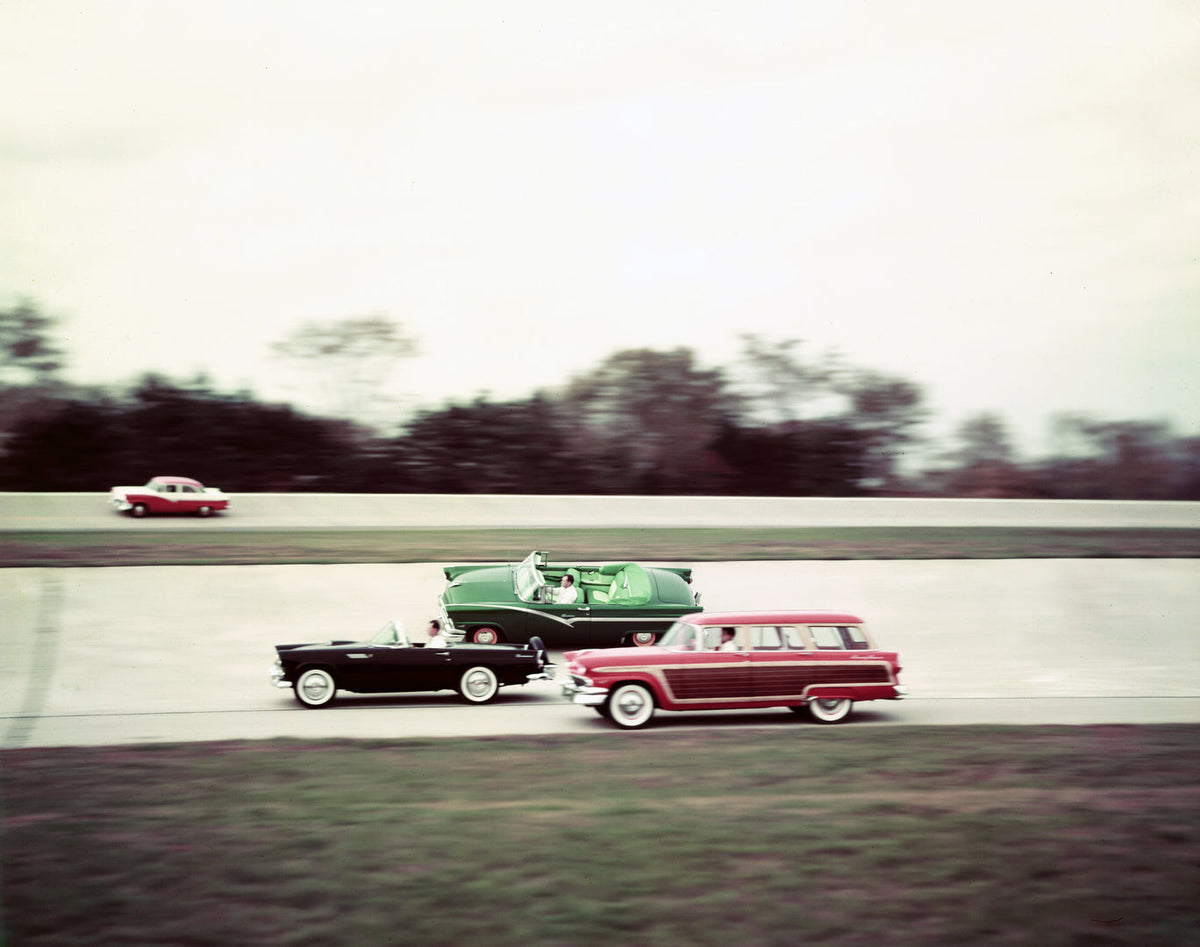 A 1956 Ford Thunderbird travels alongside a Sunliner and Country Squire on a banked test track.