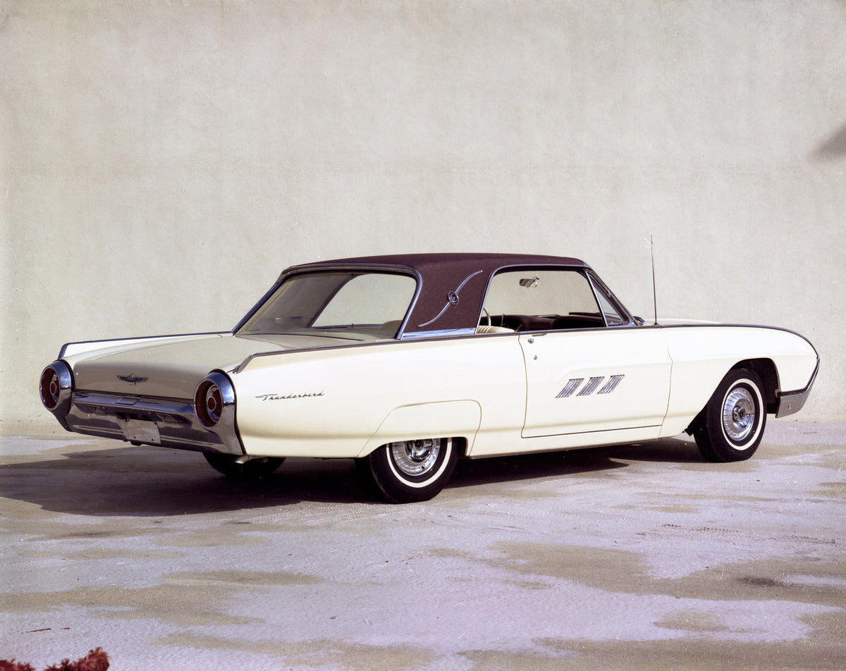A light-colored 1963 Ford Thunderbird Landau with a contrasting roof is photographed from the rear in a studio.
