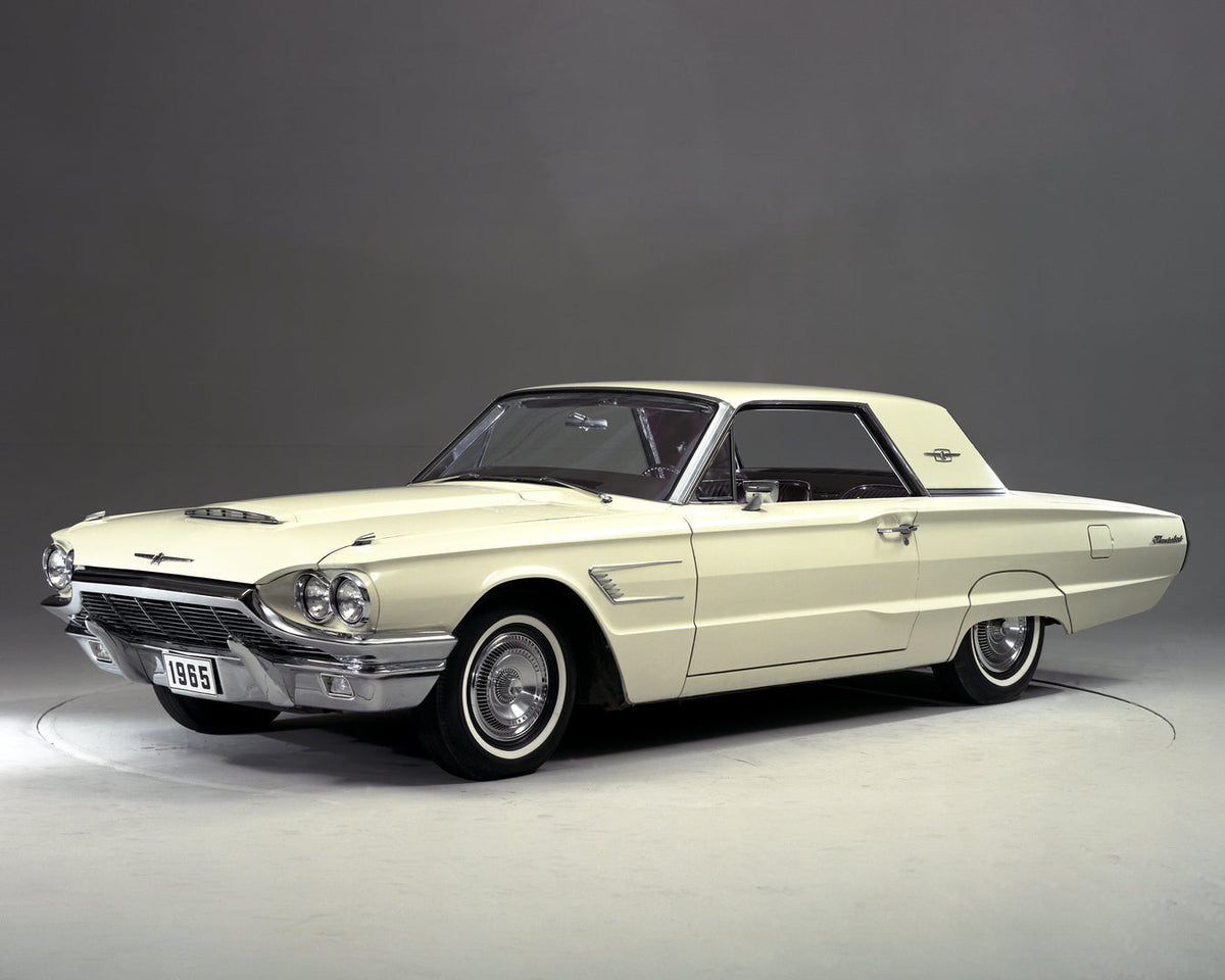 A light-colored 1965 Ford Thunderbird hardtop is photographed from the front in a studio.