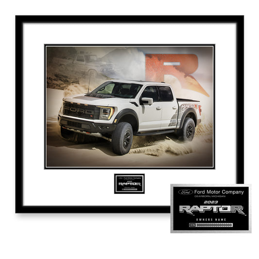 A framed and matted print of a white Ford F-150 Raptor pickup truck, displayed on a sandy background. The print includes a watermark of 'RAPTOR' and the Ford Motor Company logo, indicating it is a special edition item.