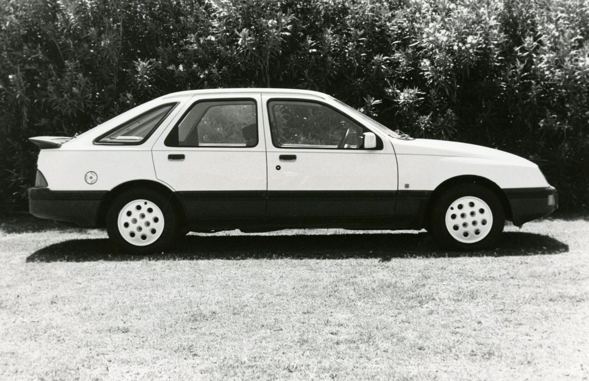 This archival image documents the 1984 Ford Sierra XR6 3.0 side view with scenic trees AR-2002-210284.7.26.2 and is preserved in the Ford Heritage Vault as part of Ford Motor Company's historic photographic archive. Free for personal, non-commerci...