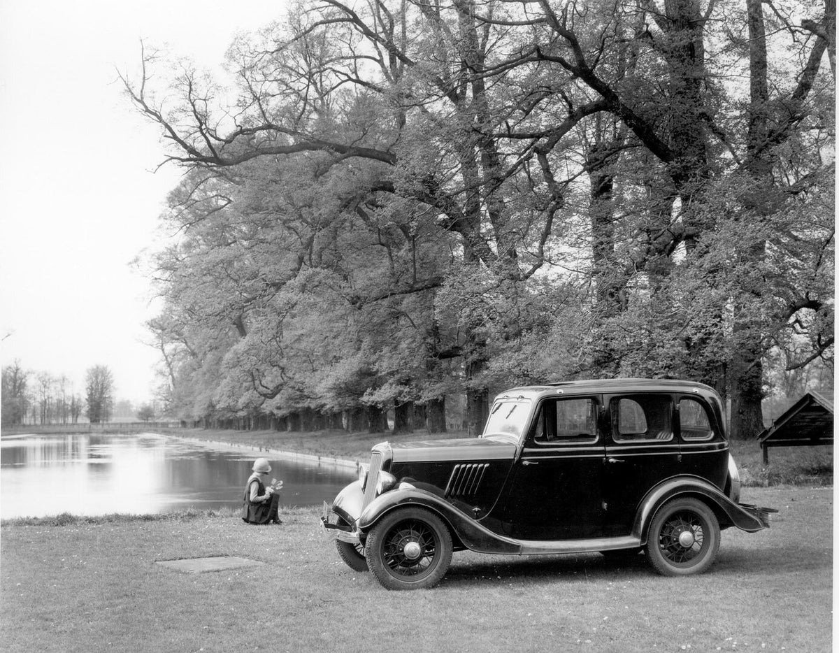 This archival image documents the 1934 Ford Model Y by scenic lake with trees AR-2002-213709 and is preserved in the Ford Heritage Vault as part of Ford Motor Company's historic photographic archive. Free for personal, non-commercial use. Ford Her...