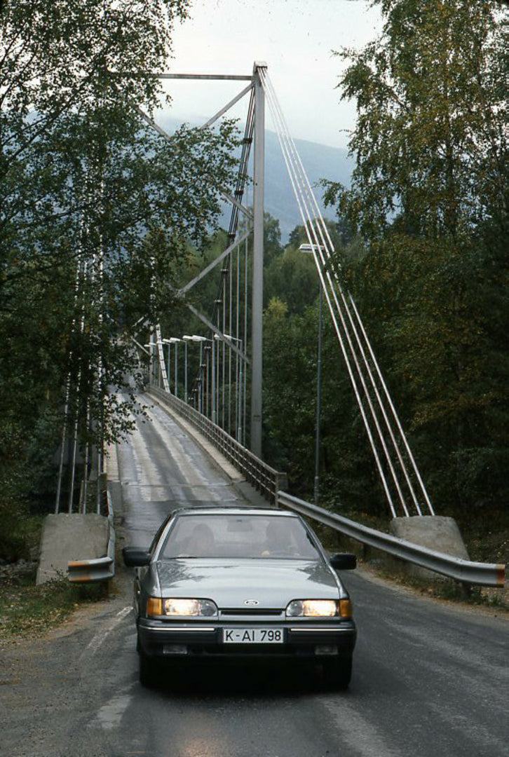 This archival image documents the 1985 Ford Scorpio Mark I Ghia front view on scenic road with bridge and is preserved in the Ford Heritage Vault as part of Ford Motor Company's historic photographic archive. Free for personal, non-commercial use....