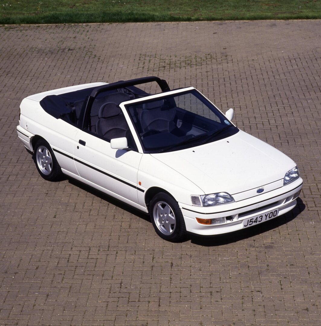 This archival image documents the 1992 Ford Escort Mark V XR3i Cabriolet aerial view on brick road and is preserved in the Ford Heritage Vault as part of Ford Motor Company's historic photographic archive. Free for personal, non-commercial use. Fo...