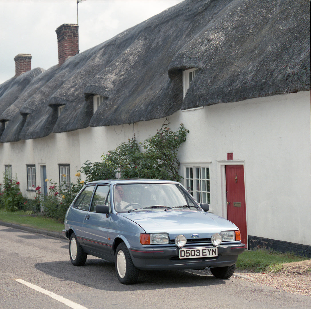 This archival image documents the 1986 Ford Fiesta Mark II 1.4 S in front of scenic building with thatch roof and is preserved in the Ford Heritage Vault as part of Ford Motor Company's historic photographic archive. Free for personal, non-commerc...