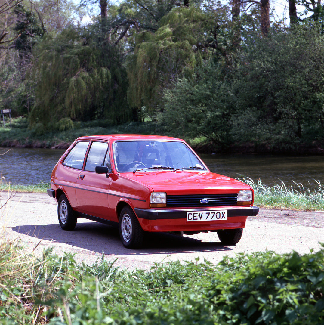This archival image documents the 1982 Ford Fiesta Mark I 1.1 L Economy on scenic road near river with trees and is preserved in the Ford Heritage Vault as part of Ford Motor Company's historic photographic archive. Free for personal, non-commerci...