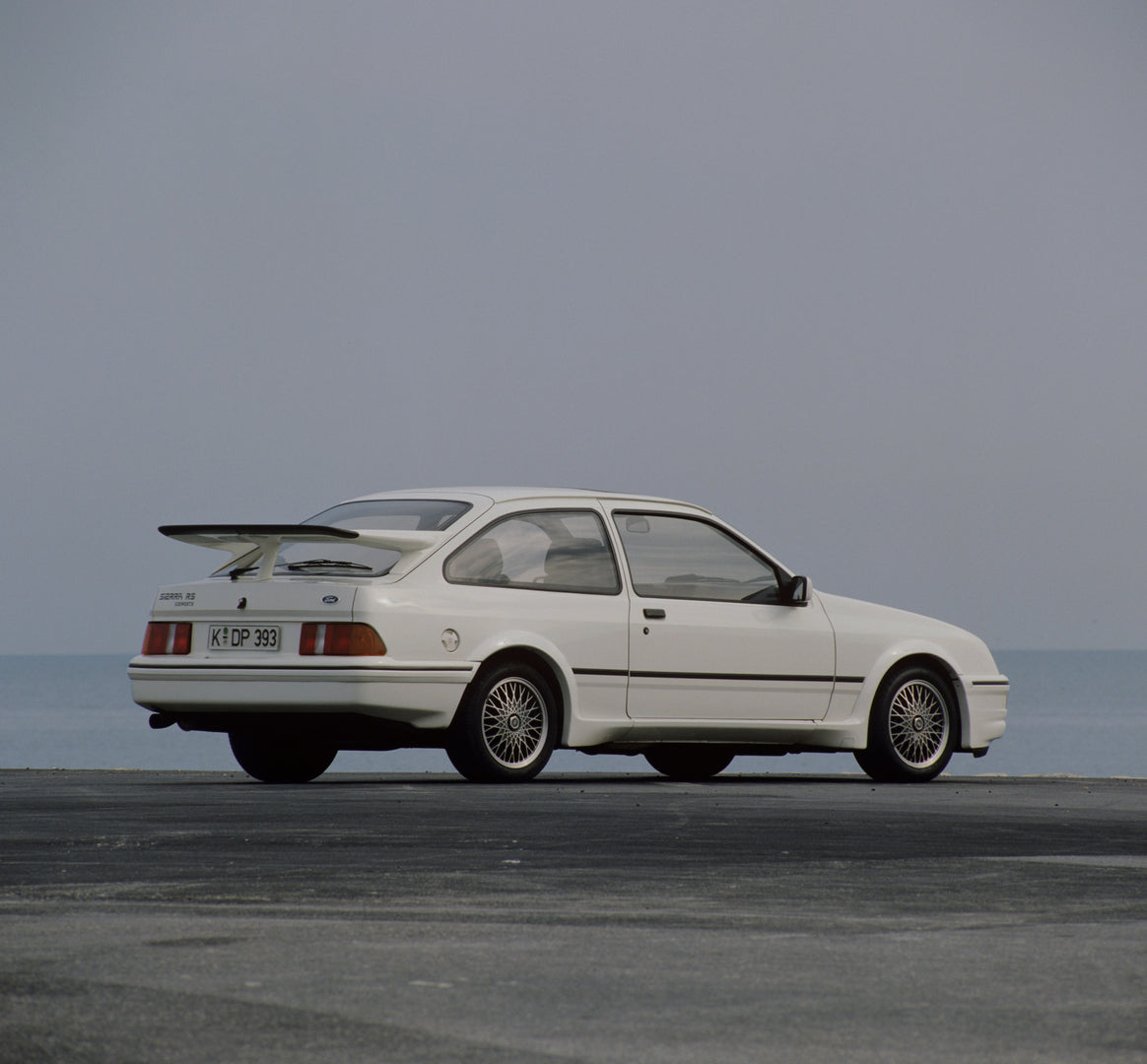 This archival image documents the 1985 Ford Sierra RS Cosworth rear view with scenic blue sky and is preserved in the Ford Heritage Vault as part of Ford Motor Company's historic photographic archive. Free for personal, non-commercial use. Ford He...