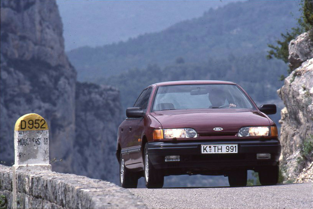 This archival image documents the 1985 Ford Granada Mark III LHD front view on scenic road and is preserved in the Ford Heritage Vault as part of Ford Motor Company's historic photographic archive. Free for personal, non-commercial use. Ford Herit...