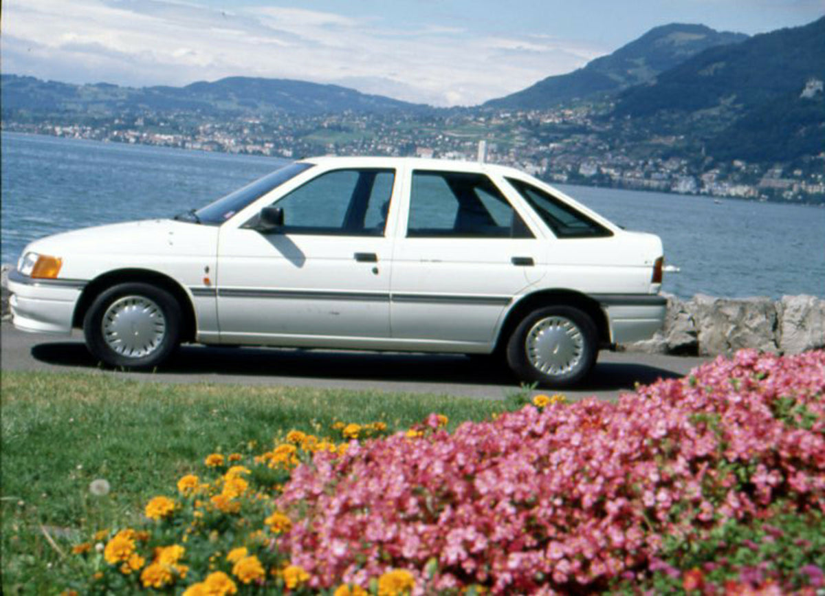 This archival image documents the 1990 Ford Escort Ghia Mark IV on scenic road in Geneva, Switzerland and is preserved in the Ford Heritage Vault as part of Ford Motor Company's historic photographic archive. Free for personal, non-commercial use....