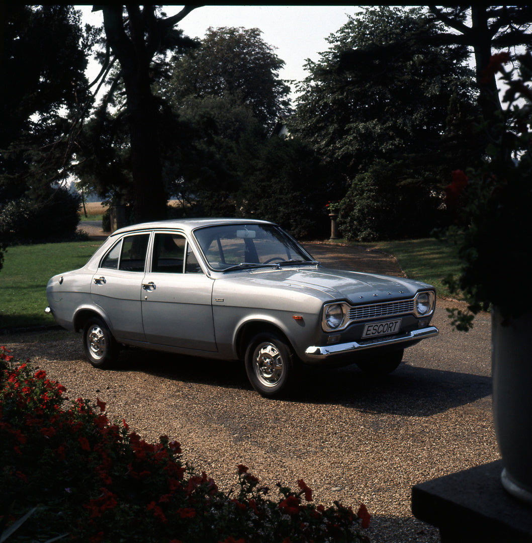 This archival image documents the 1969 Ford Escort Mark I Deluxe 4 Door LHD in scenic driveway and is preserved in the Ford Heritage Vault as part of Ford Motor Company's historic photographic archive. Free for personal, non-commercial use. Ford H...