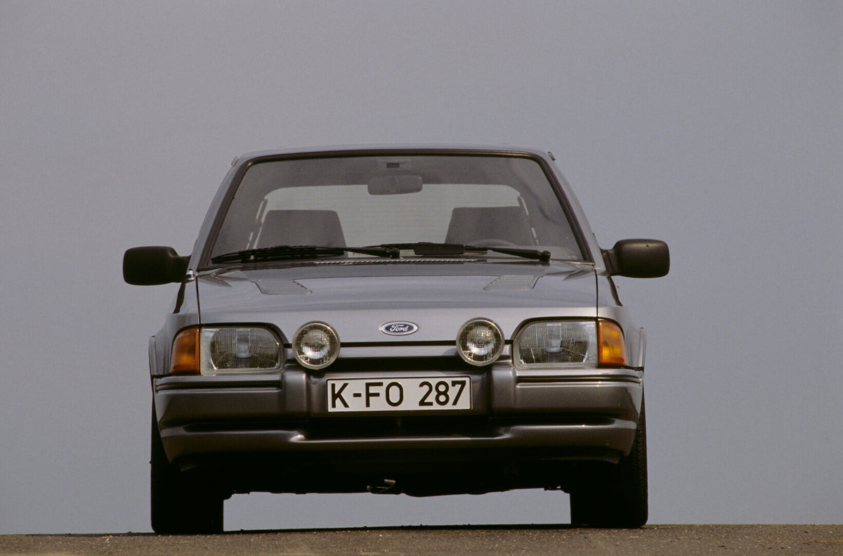 This archival image documents the 1986 Ford Escort Mark IV RS Turbo front view with scenic blue sky and is preserved in the Ford Heritage Vault as part of Ford Motor Company's historic photographic archive. Free for personal, non-commercial use. F...