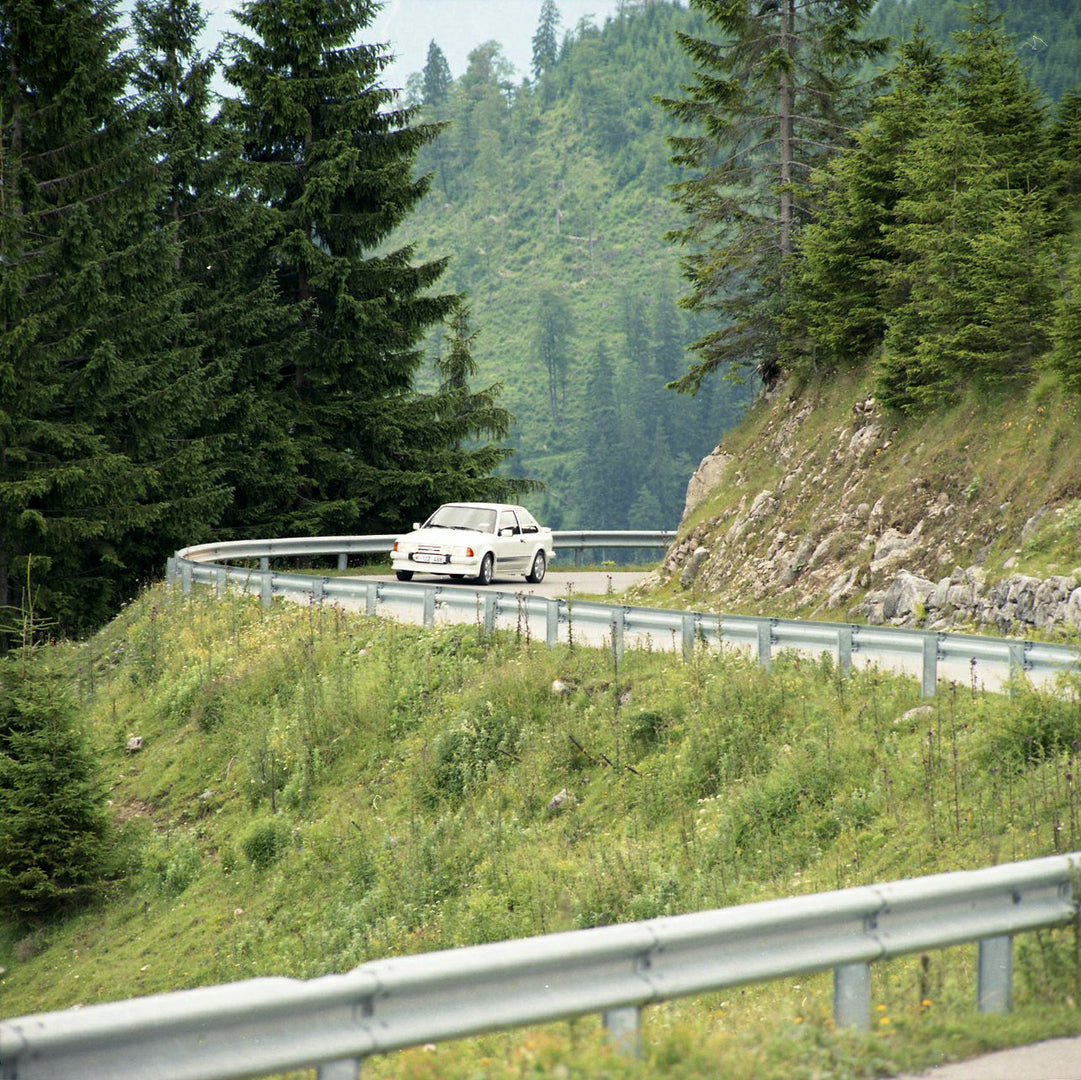 This archival image documents the 1984 Ford Escort Mark III LHD RS Turbo in distance on scenic road in Munich and is preserved in the Ford Heritage Vault as part of Ford Motor Company's historic photographic archive. Free for personal, non-commerc...