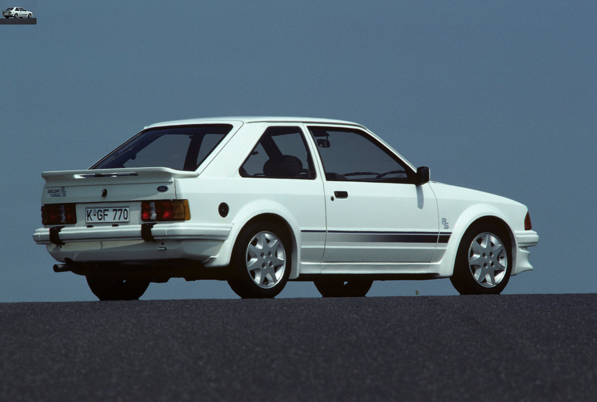 This archival image documents the 1984 Ford Escort Mark III RS Turbo rear view with scenic blue sky and is preserved in the Ford Heritage Vault as part of Ford Motor Company's historic photographic archive. Free for personal, non-commercial use. F...