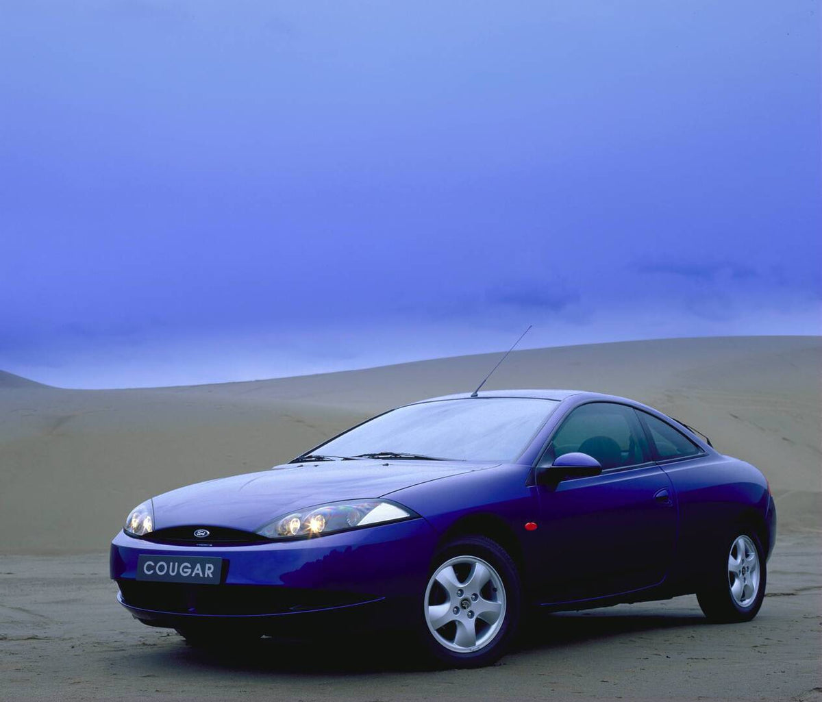 This archival image documents the 1998 Ford Cougar low view in scenic desert AR-2002-213709 and is preserved in the Ford Heritage Vault as part of Ford Motor Company's historic photographic archive. Free for personal, non-commercial use. Ford Heri...