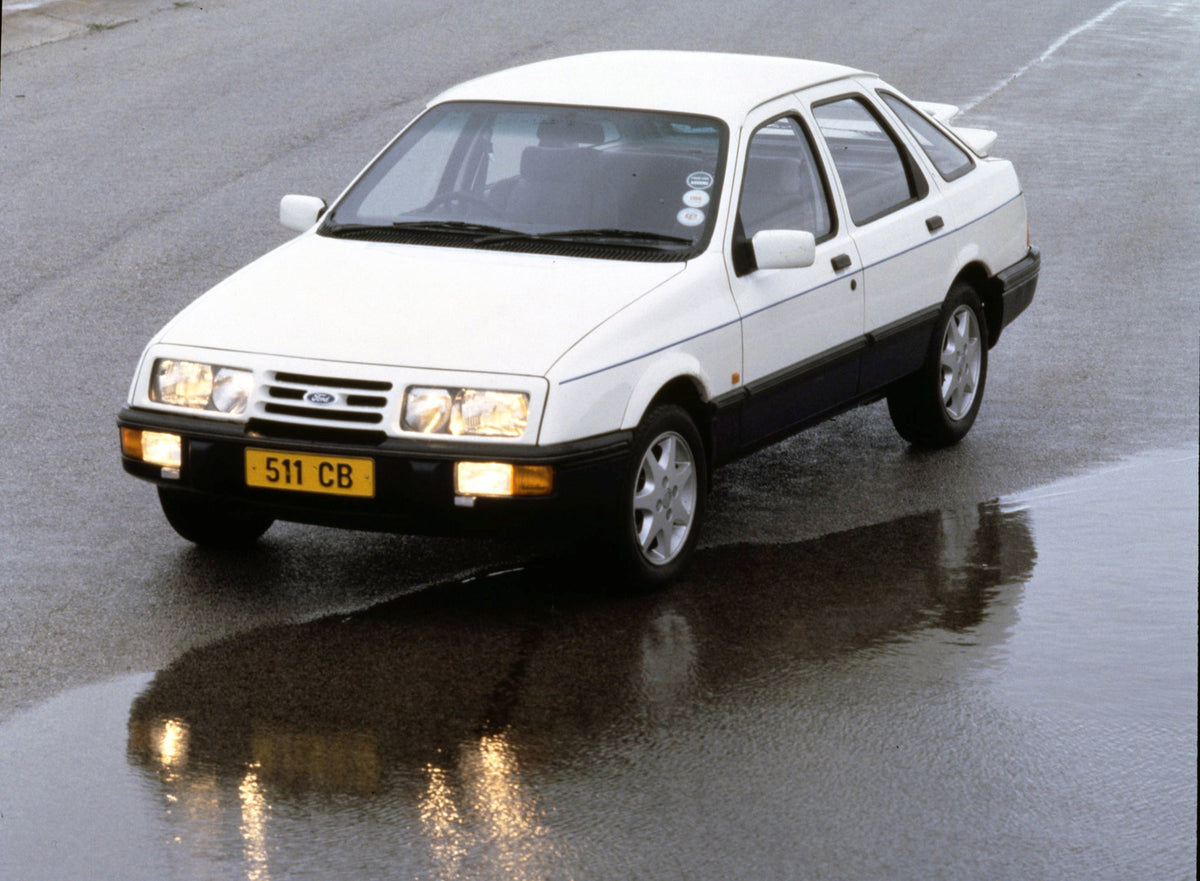 This archival image documents the 1984 Ford Sierra XR8 on road with puddle and is preserved in the Ford Heritage Vault as part of Ford Motor Company's historic photographic archive. Free for personal, non-commercial use. Ford Heritage Vault refere...