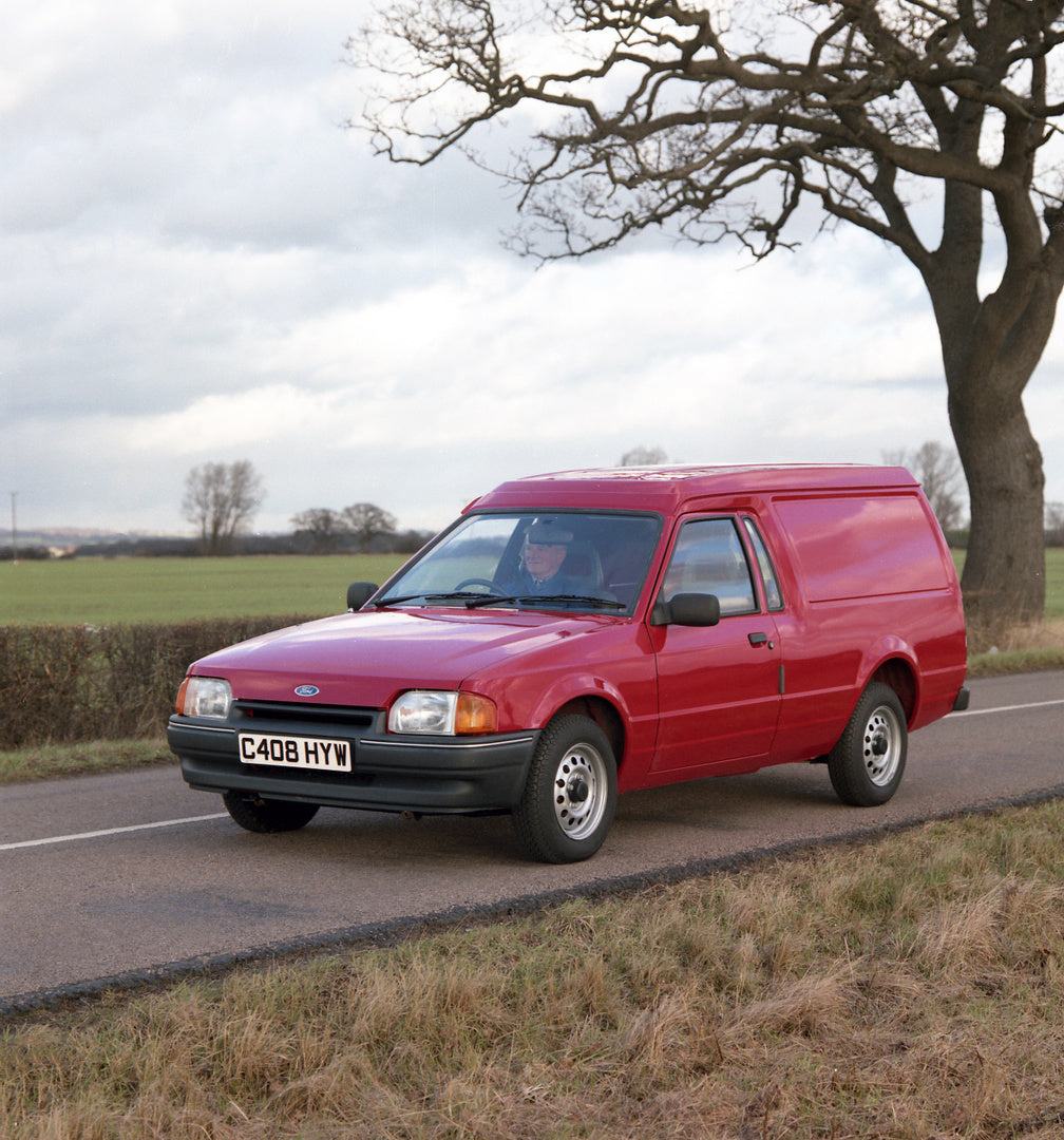 This archival image documents the 1986 Ford Escort Mark IV 6/8 Counterweight Van RHD on scenic road with tree and is preserved in the Ford Heritage Vault as part of Ford Motor Company's historic photographic archive. Free for personal, non-commerc...