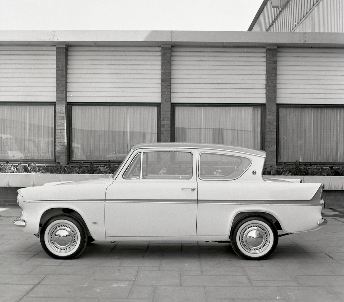 This archival image documents the 1963 Ford Anglia Super side view in front of building and is preserved in the Ford Heritage Vault as part of Ford Motor Company's historic photographic archive. Free for personal, non-commercial use. Ford Heritage...