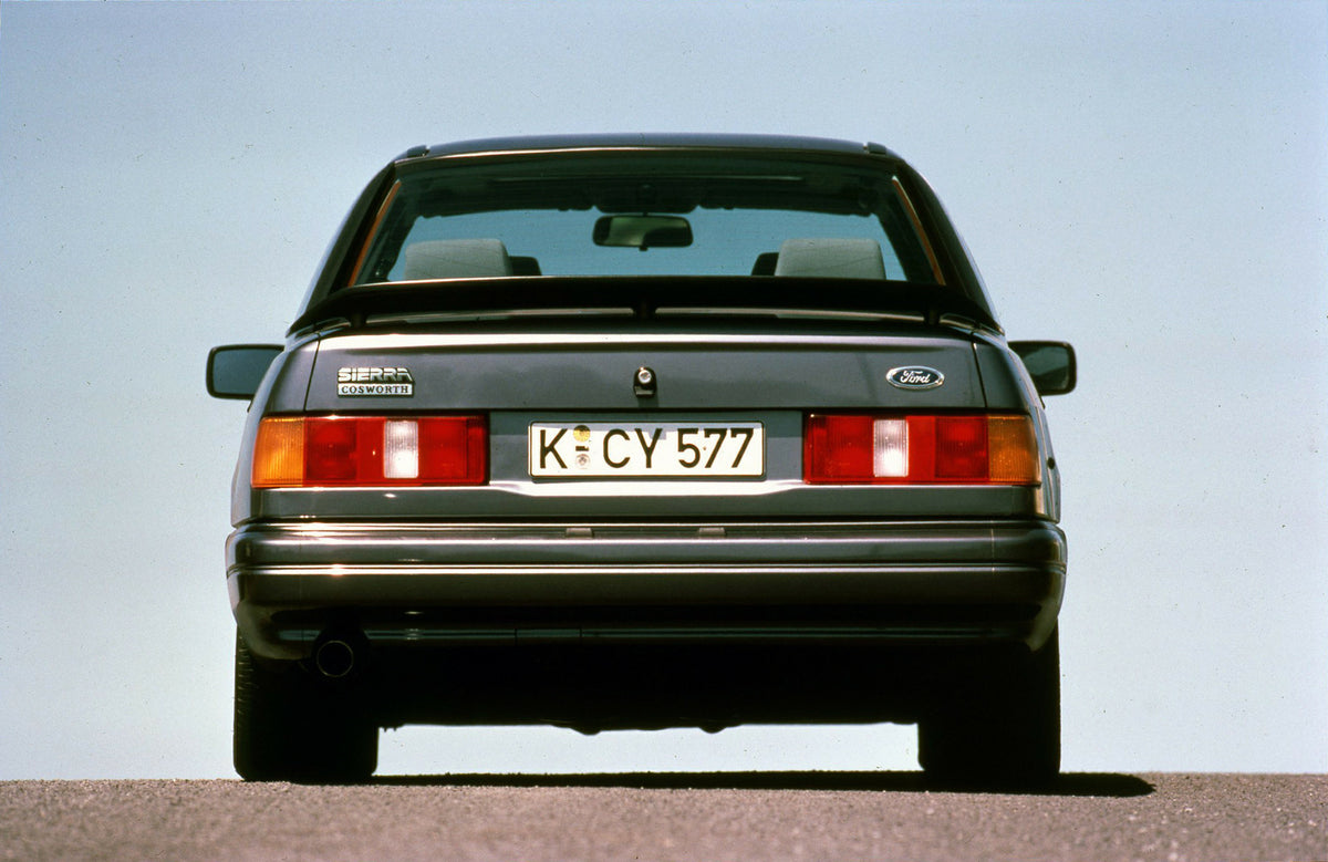 This archival image documents the 1987 Ford Sierra RS Cosworth rear view with scenic blue sky and is preserved in the Ford Heritage Vault as part of Ford Motor Company's historic photographic archive. Free for personal, non-commercial use. Ford He...