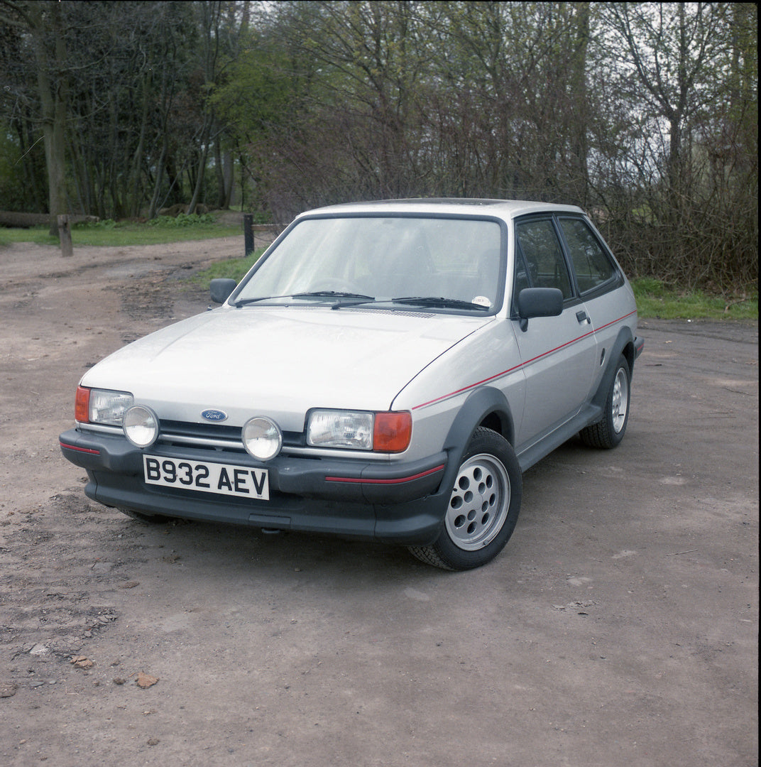 This archival image documents the 1985 Ford Fiesta Mark II XR2 on scenic road with trees and is preserved in the Ford Heritage Vault as part of Ford Motor Company's historic photographic archive. Free for personal, non-commercial use. Ford Heritag...