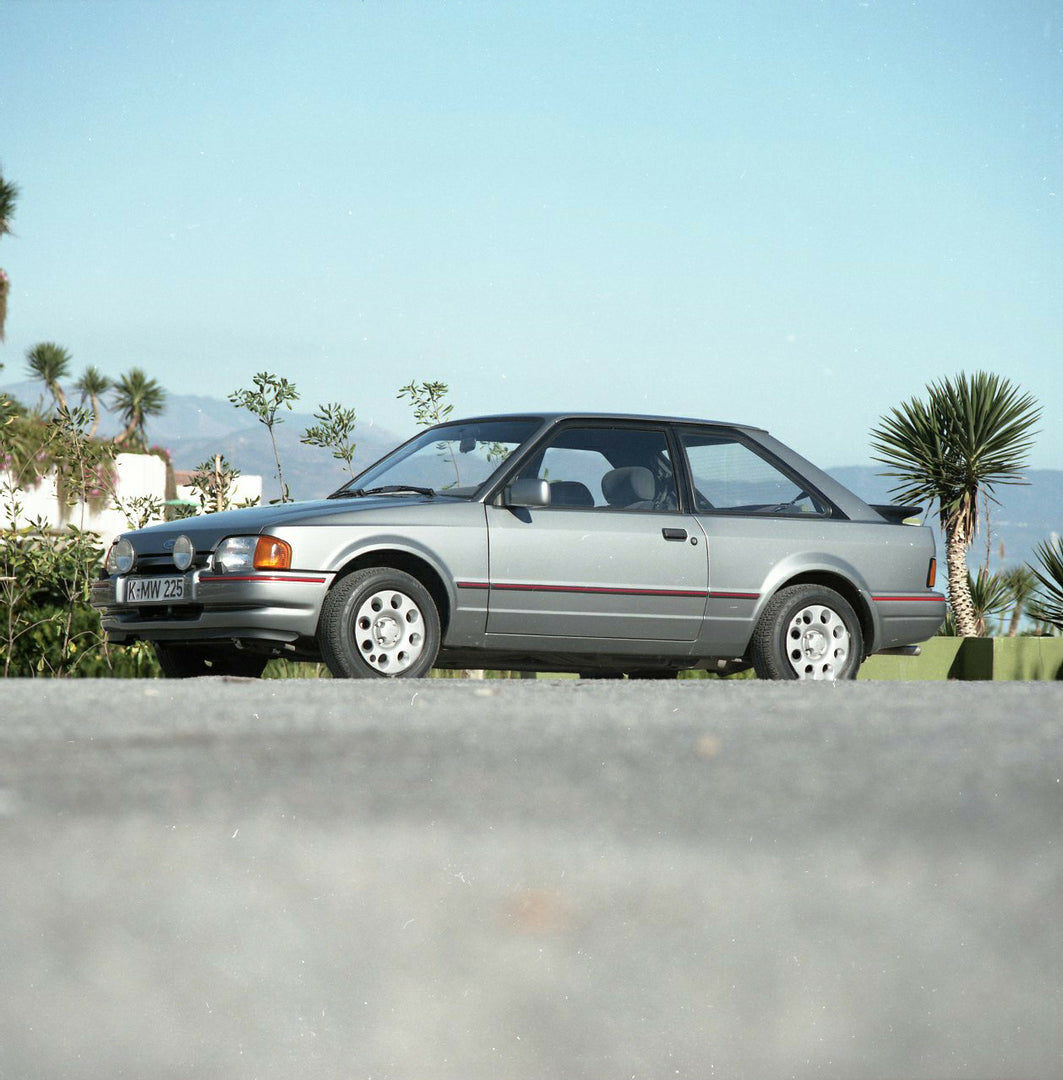This archival image documents the 1985 Ford Escort Mark IV XR3i LHD low side view on scenic road and is preserved in the Ford Heritage Vault as part of Ford Motor Company's historic photographic archive. Free for personal, non-commercial use. Ford...