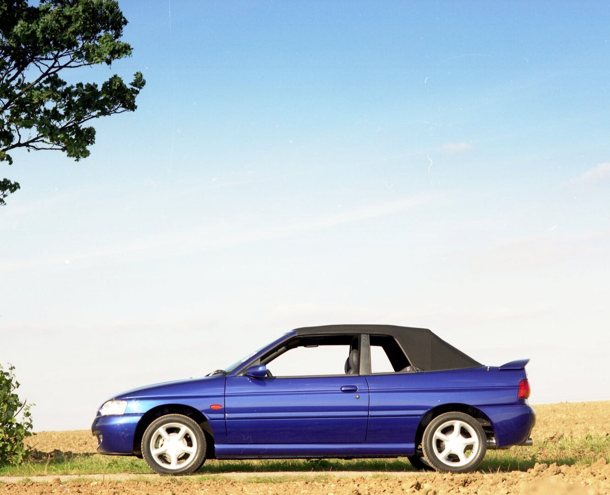This archival image documents the 1996 Ford Escort Mark VI Cabriolet Ghia side view on scenic road with top up and is preserved in the Ford Heritage Vault as part of Ford Motor Company's historic photographic archive. Free for personal, non-commer...