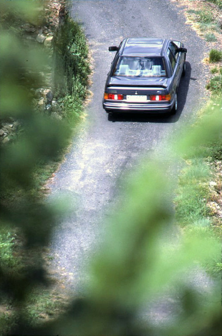 This archival image documents the 1987 Ford Sierra RS Cosworth rear aerial view on scenic road vertical shot and is preserved in the Ford Heritage Vault as part of Ford Motor Company's historic photographic archive. Free for personal, non-commerci...