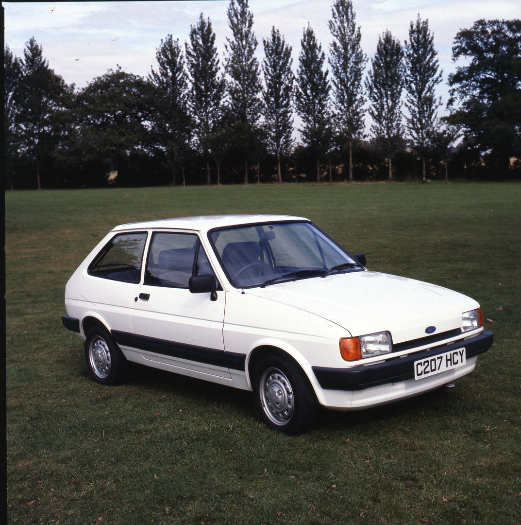 This archival image documents the 1985 Ford Fiesta Mark II 1.3 L in scenic field with trees and is preserved in the Ford Heritage Vault as part of Ford Motor Company's historic photographic archive. Free for personal, non-commercial use. Ford Heri...