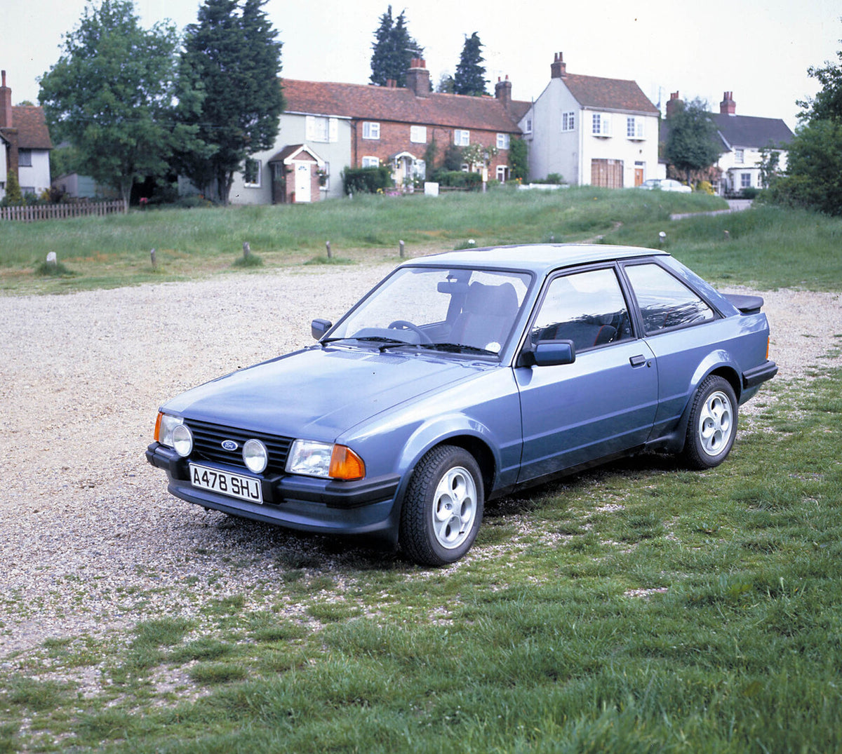 This archival image documents the 1984 Ford Escort Mark III XR3i on scenic road with houses 1984-583 and is preserved in the Ford Heritage Vault as part of Ford Motor Company's historic photographic archive. Free for personal, non-commercial use. ...