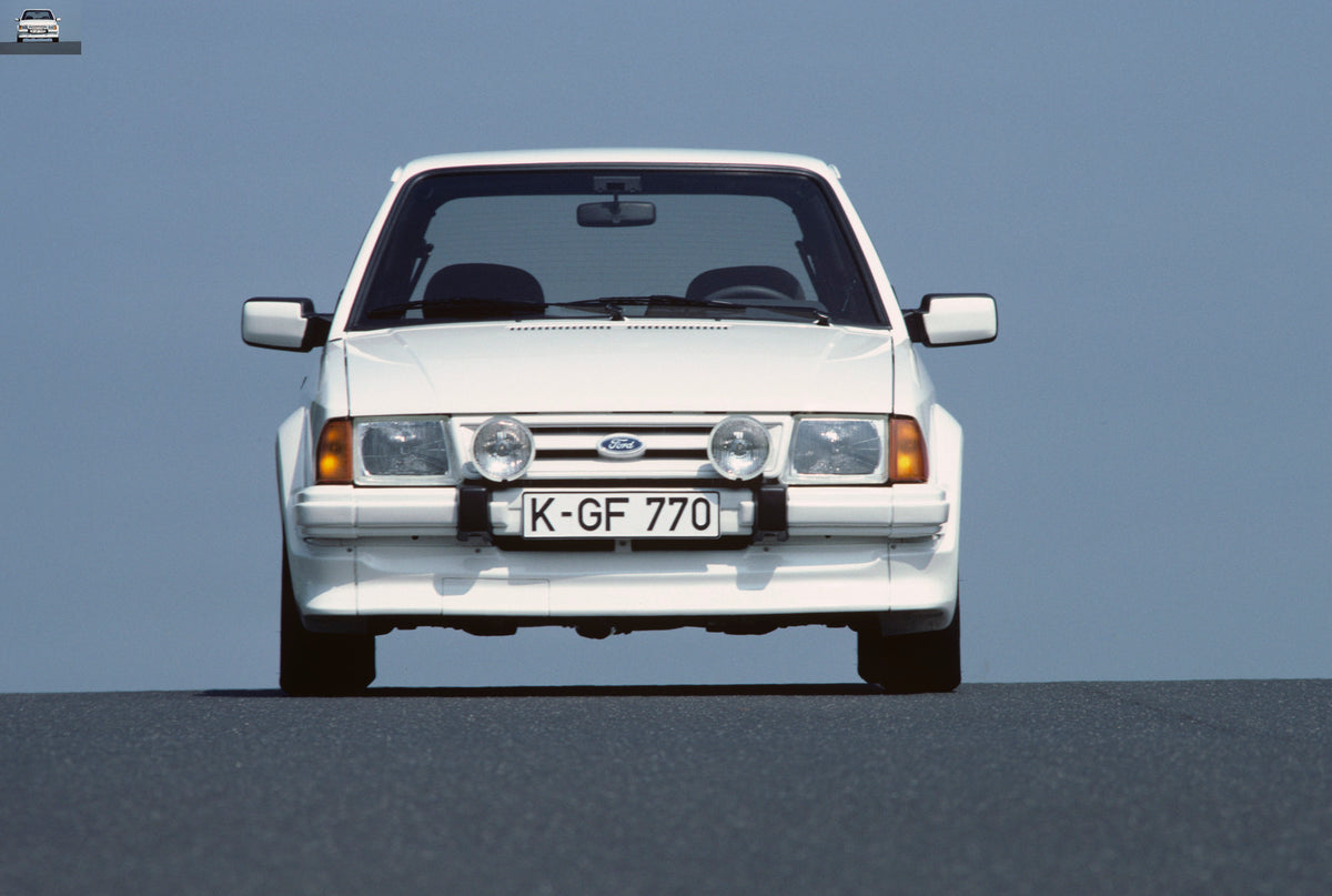 This archival image documents the 1984 Ford Escort Mark III RS Turbo front view with scenic blue sky and is preserved in the Ford Heritage Vault as part of Ford Motor Company's historic photographic archive. Free for personal, non-commercial use. ...