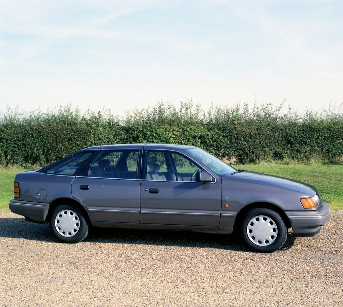 This archival image documents the 1987 Ford Granada Ghia 2.4i side view on scenic road with shrubs and is preserved in the Ford Heritage Vault as part of Ford Motor Company's historic photographic archive. Free for personal, non-commercial use. Fo...