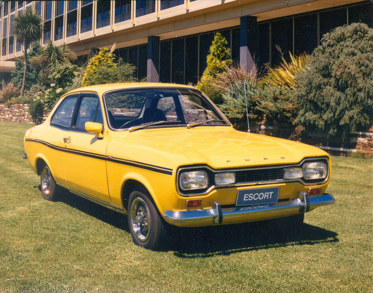 This archival image documents the 1970 Ford Escort Mark I in front of scenic building with trees and hedges and is preserved in the Ford Heritage Vault as part of Ford Motor Company's historic photographic archive. Free for personal, non-commercia...