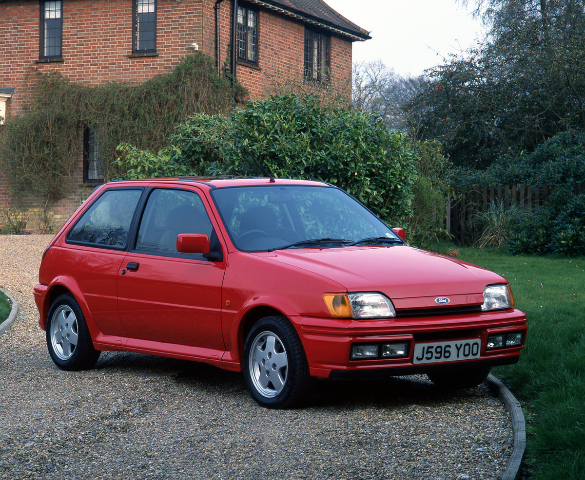 This archival image documents the 1992 Ford Fiesta Mark III XR2i in driveway of scenic house and is preserved in the Ford Heritage Vault as part of Ford Motor Company's historic photographic archive. Free for personal, non-commercial use. Ford Her...