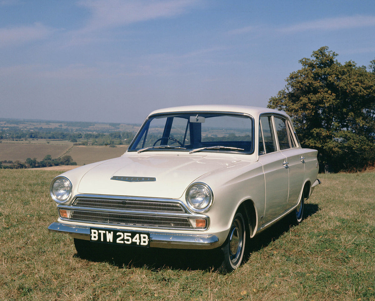 This archival image documents the 1964 Ford Cortina GT Mark I in scenic field with tree and is preserved in the Ford Heritage Vault as part of Ford Motor Company's historic photographic archive. Free for personal, non-commercial use. Ford Heritage...