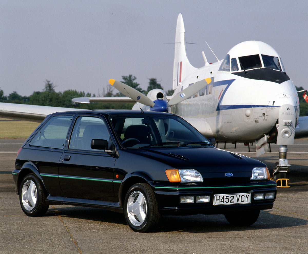 This archival image documents the 1990 Ford Fiesta Mark III Turbo on tarmac with plane and is preserved in the Ford Heritage Vault as part of Ford Motor Company's historic photographic archive. Free for personal, non-commercial use. Ford Heritage ...