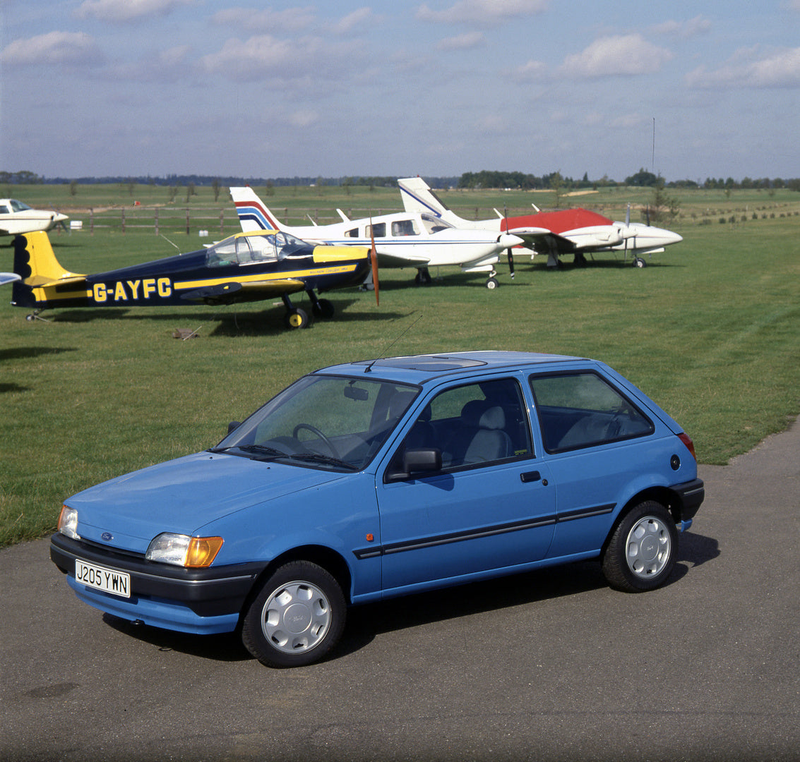 This archival image documents the 1991 Ford Fiesta Mark III 1.1 LX in field with planes and is preserved in the Ford Heritage Vault as part of Ford Motor Company's historic photographic archive. Free for personal, non-commercial use. Ford Heritage...