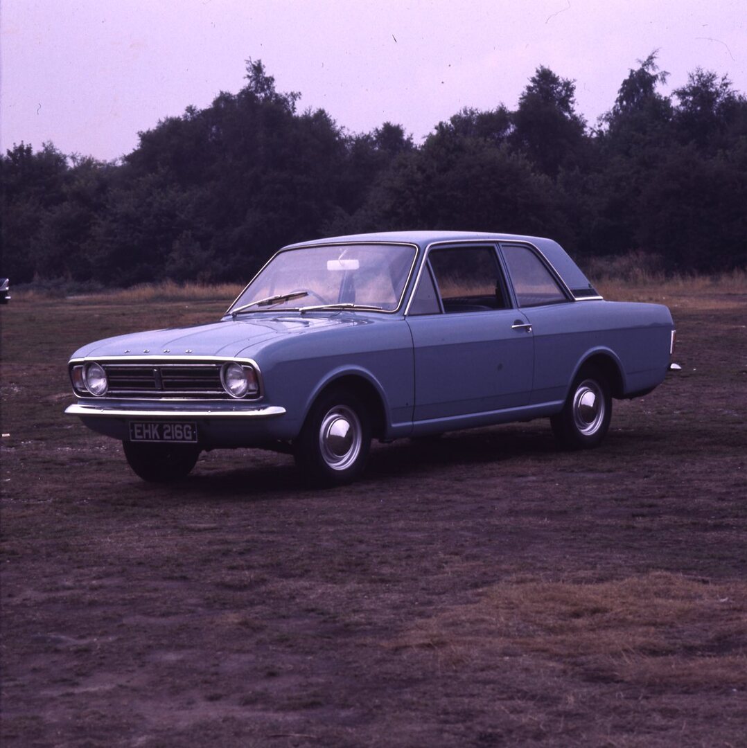 This archival image documents the 1969 Ford Cortina MK II DL 1300 2 door in scenic field with trees and is preserved in the Ford Heritage Vault as part of Ford Motor Company's historic photographic archive. Free for personal, non-commercial use. F...