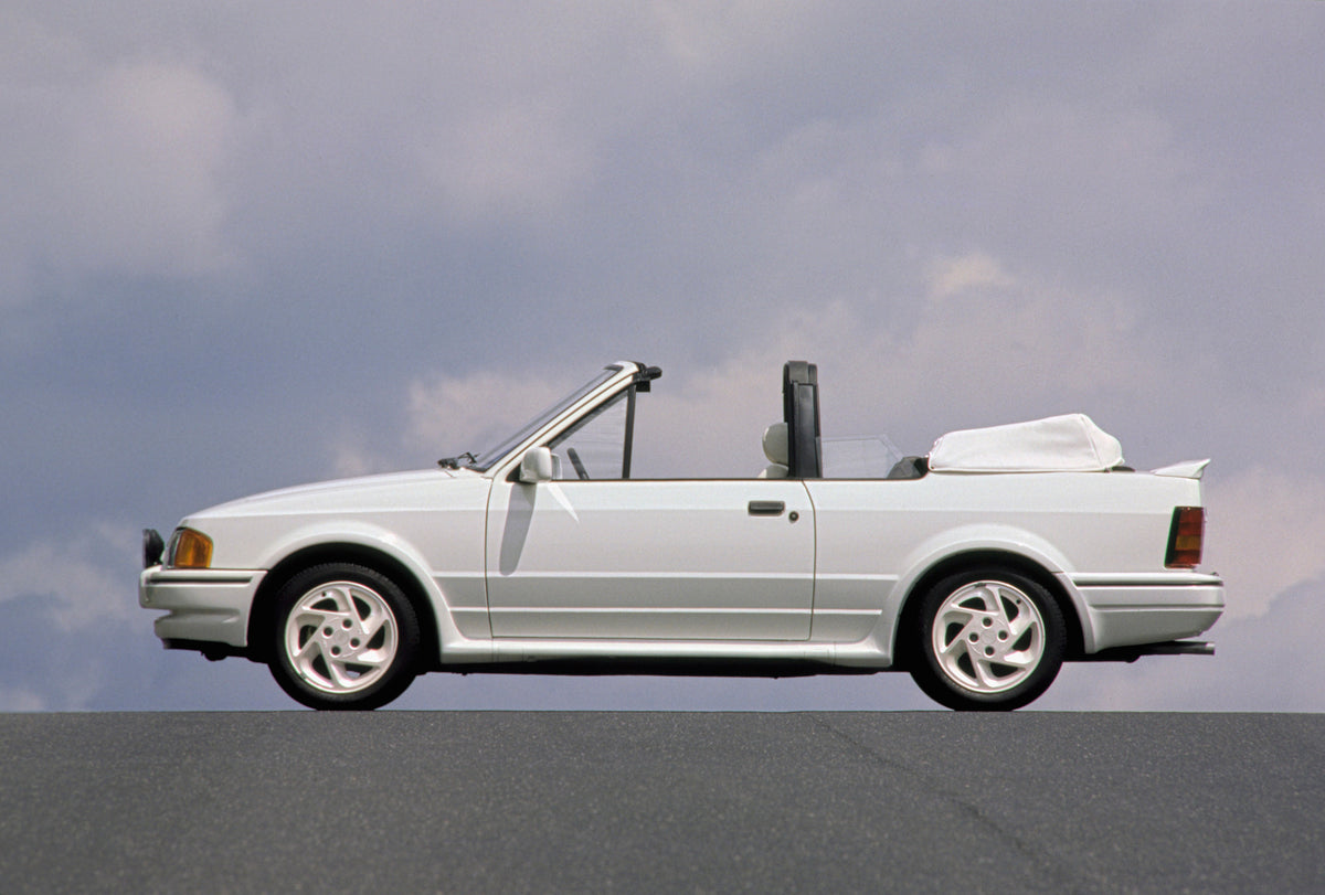 This archival image documents the 1988 Ford Escort Mark IV XR3i Cabriolet side view with scenic blue sky and is preserved in the Ford Heritage Vault as part of Ford Motor Company's historic photographic archive. Free for personal, non-commercial u...