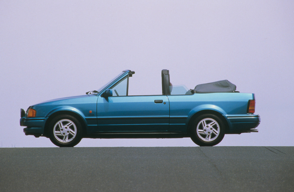 This archival image documents the 1990 Ford Escort Mark IV XR3i Cabriolet side view with scenic blue sky and is preserved in the Ford Heritage Vault as part of Ford Motor Company's historic photographic archive. Free for personal, non-commercial u...
