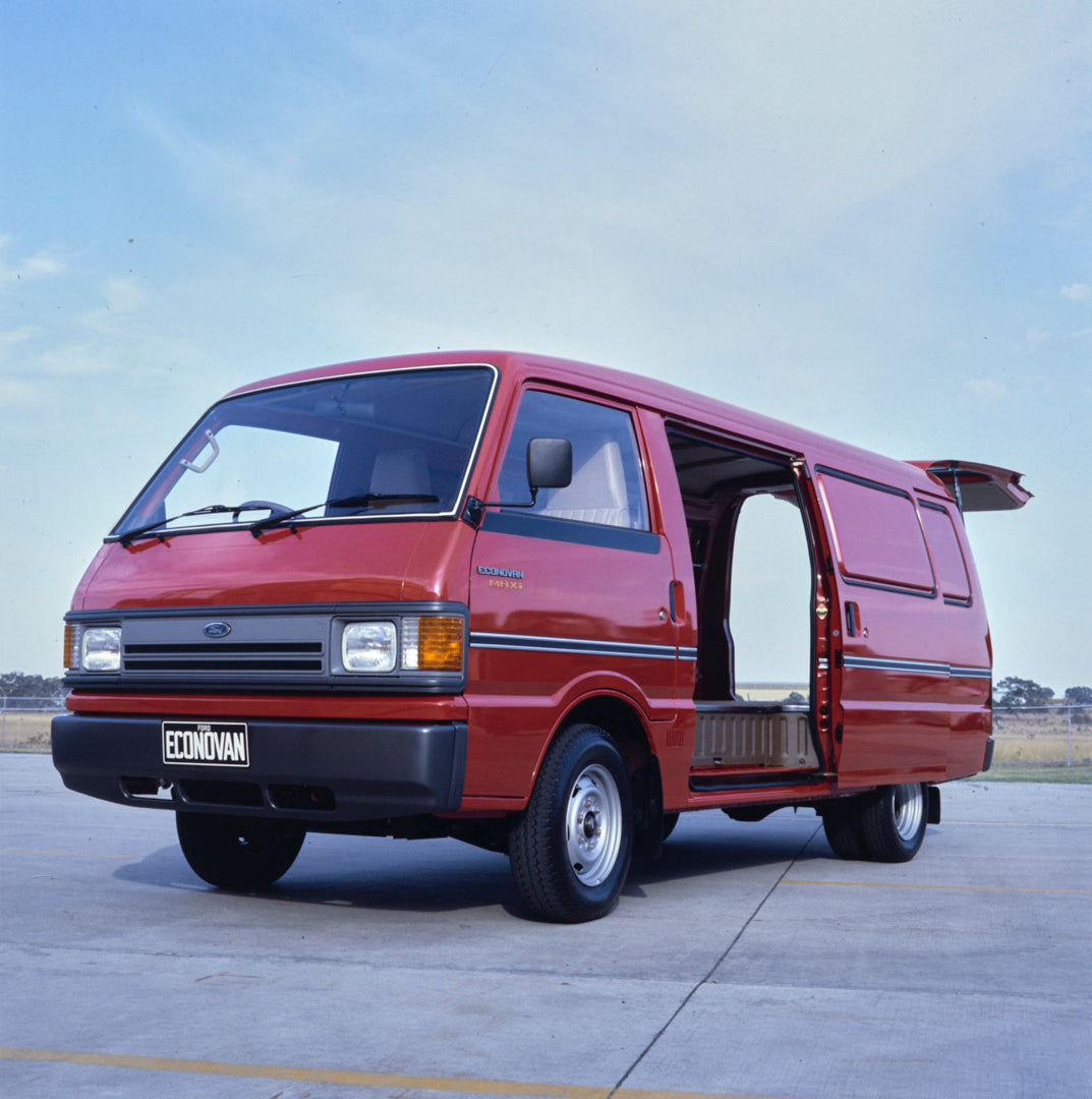 This archival image documents the 1984 Ford Econovan MAXi Passenger Side Front End View, with Rear Sliding Door Open, in Empty Lot FAP-2011-3 and is preserved in the Ford Heritage Vault as part of Ford Motor Company's historic photographic archive...