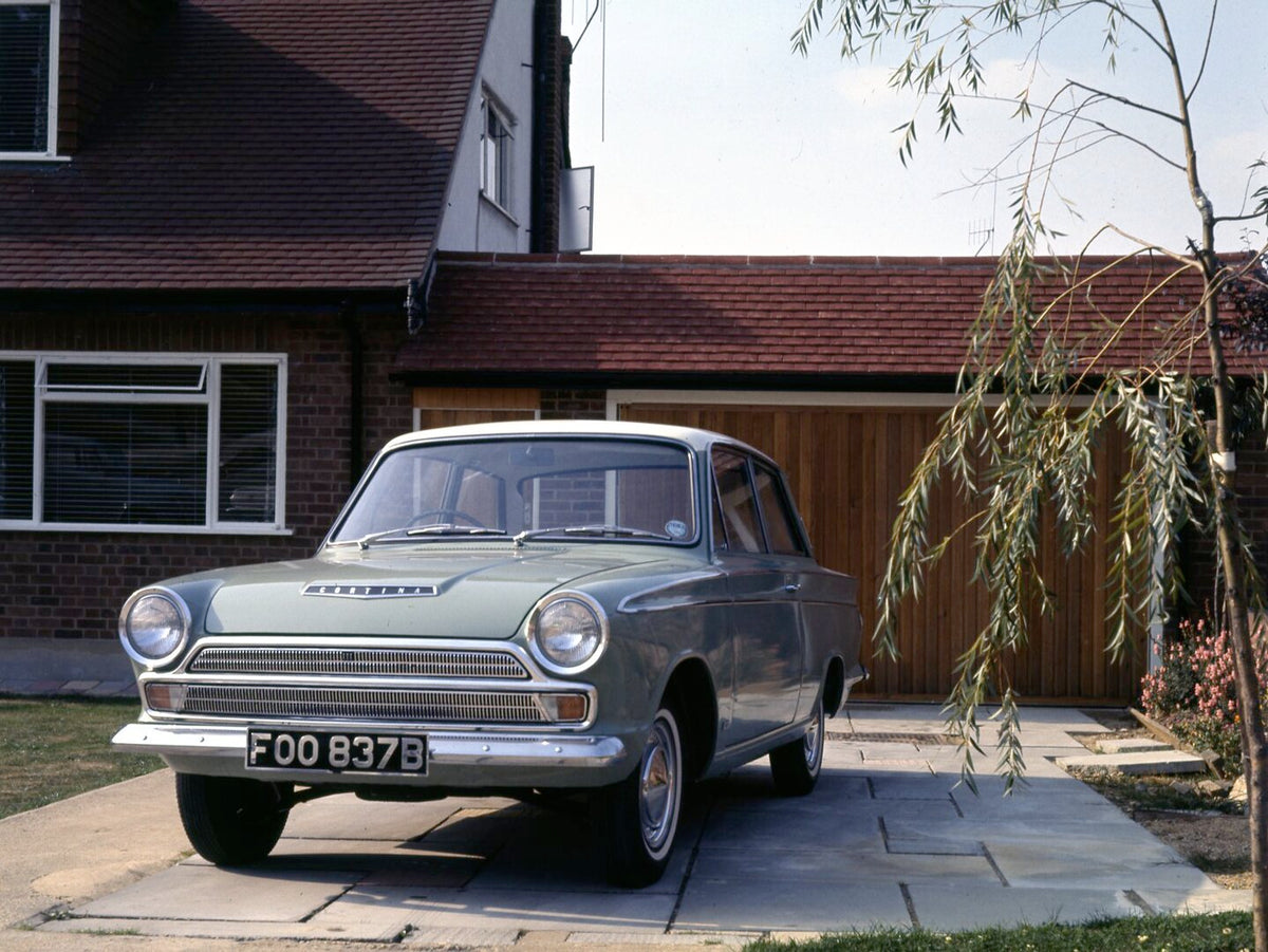 This archival image documents the 1964 Ford Cortina Super MK I front view in driveway of house and is preserved in the Ford Heritage Vault as part of Ford Motor Company's historic photographic archive. Free for personal, non-commercial use. Ford H...
