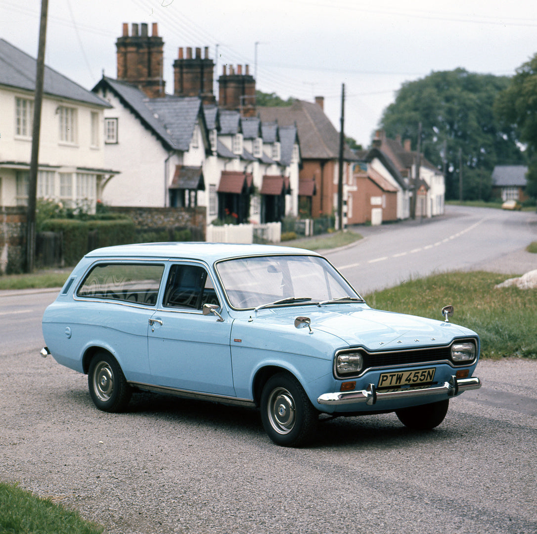 This archival image documents the 1974 Ford Escort Mark I Estate 1300 XL on scenic road with houses and is preserved in the Ford Heritage Vault as part of Ford Motor Company's historic photographic archive. Free for personal, non-commercial use. F...