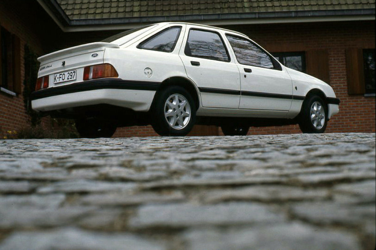 This archival image documents the 1985 Ford Sierra XR 4x4 LHD low view in driveway and is preserved in the Ford Heritage Vault as part of Ford Motor Company's historic photographic archive. Free for personal, non-commercial use. Ford Heritage Vaul...