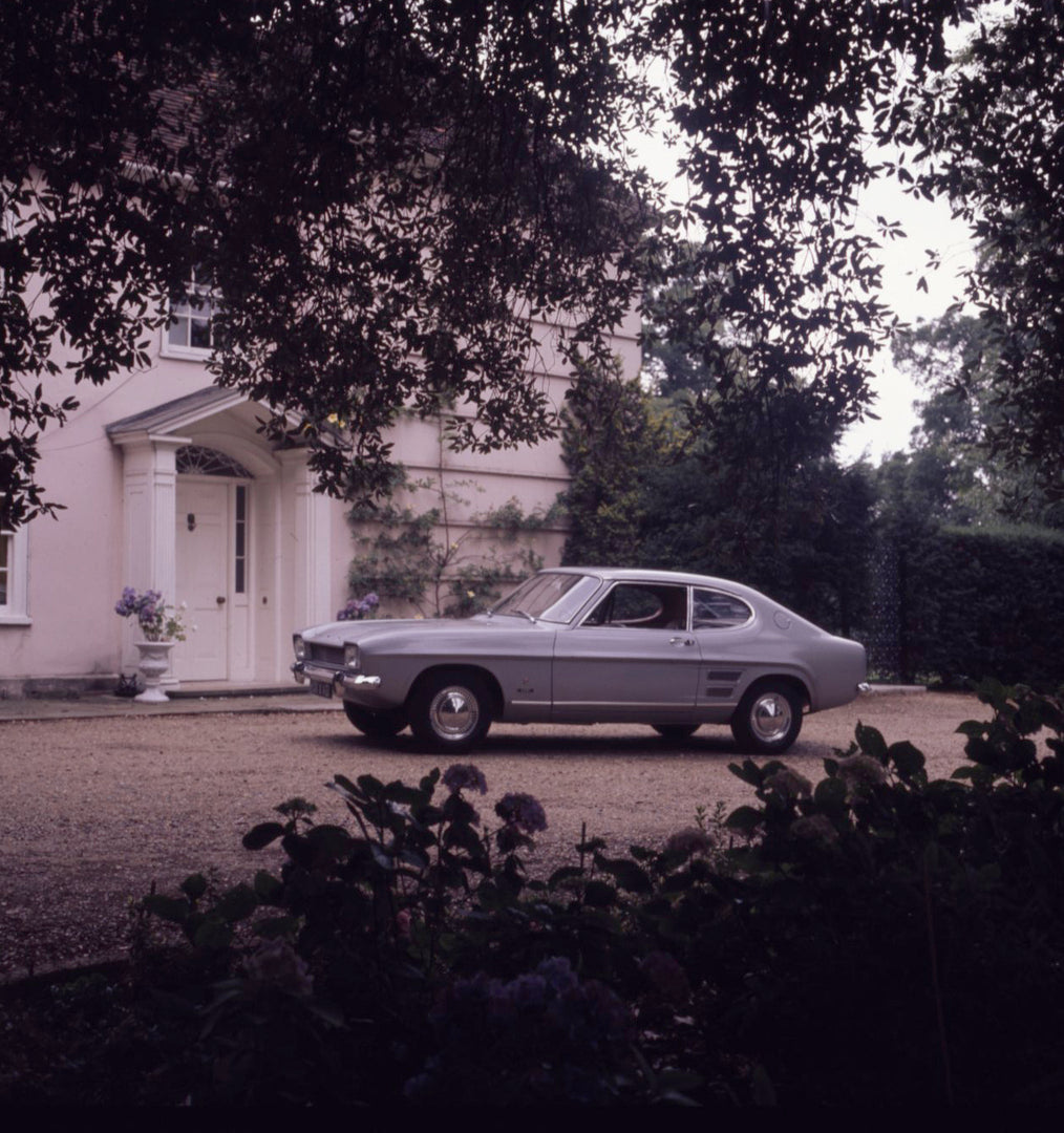 This archival image documents the 1970 Ford Capri MK I 1300L in front of scenic house with trees and is preserved in the Ford Heritage Vault as part of Ford Motor Company's historic photographic archive. Free for personal, non-commercial use. Ford...