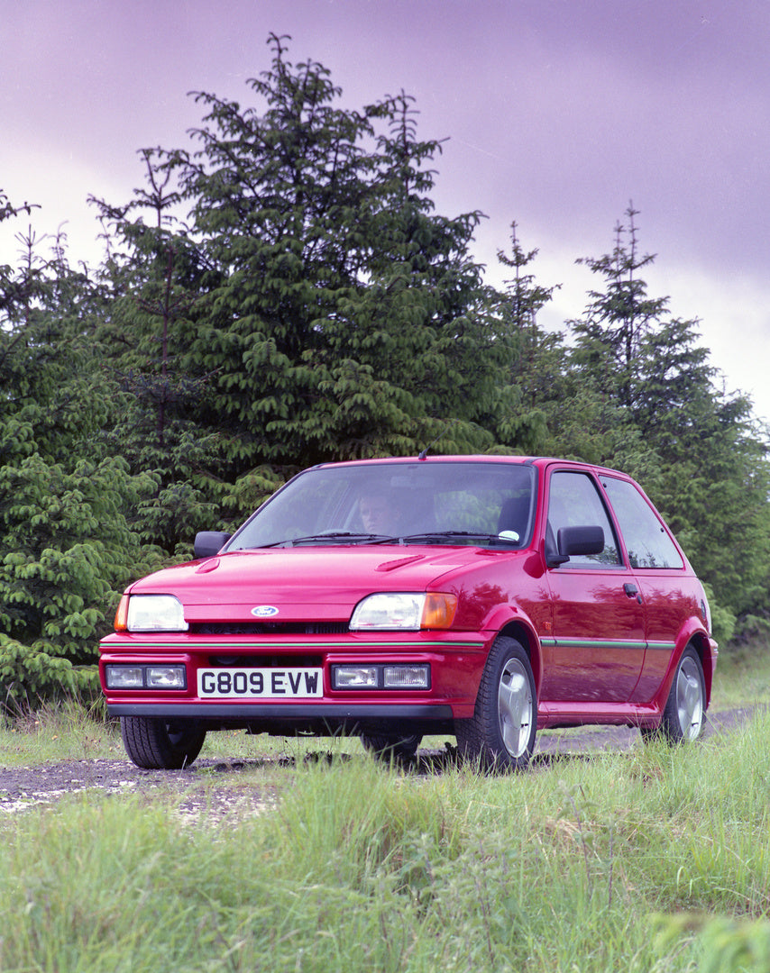 This archival image documents the 1990 Ford Fiesta Mark III Turbo on scenic road with trees in Northern Ireland and is preserved in the Ford Heritage Vault as part of Ford Motor Company's historic photographic archive. Free for personal, non-comme...
