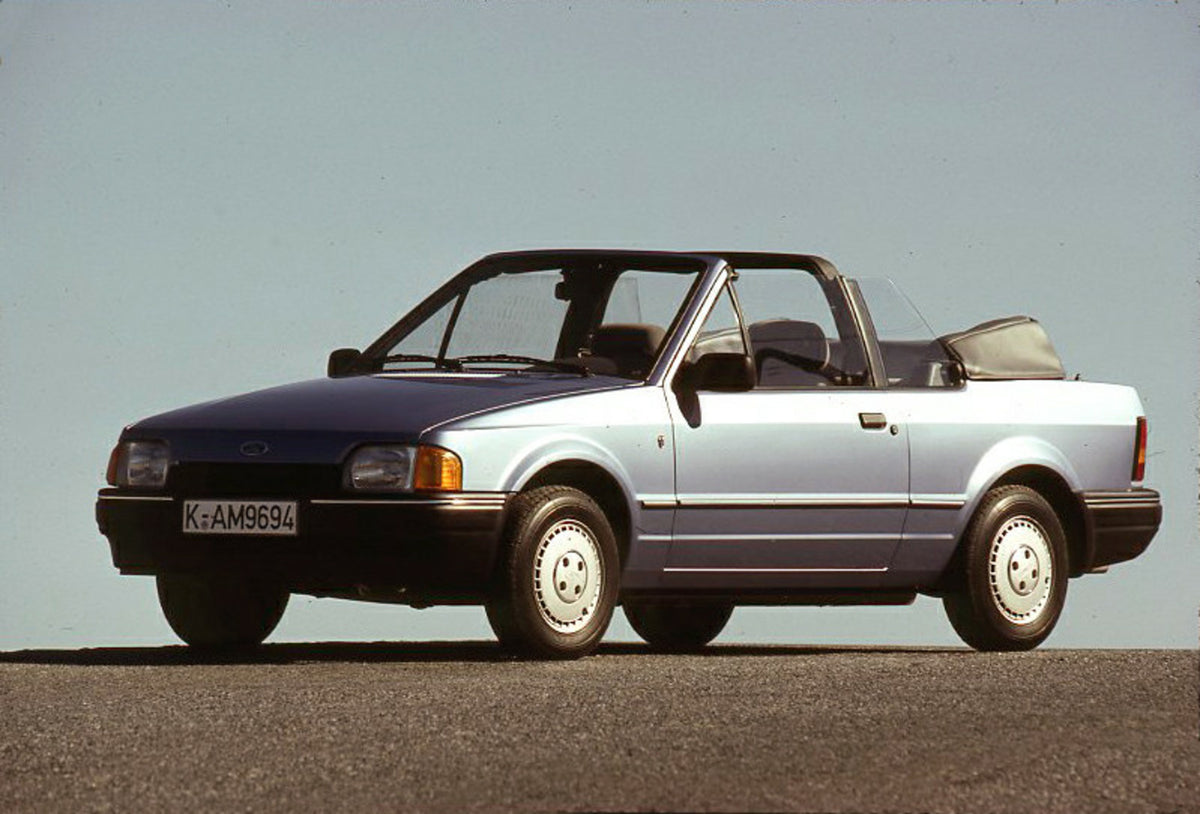 This archival image documents the 1986 Ford Escort Mark IV Cabriolet with scenic blue sky and is preserved in the Ford Heritage Vault as part of Ford Motor Company's historic photographic archive. Free for personal, non-commercial use. Ford Herita...