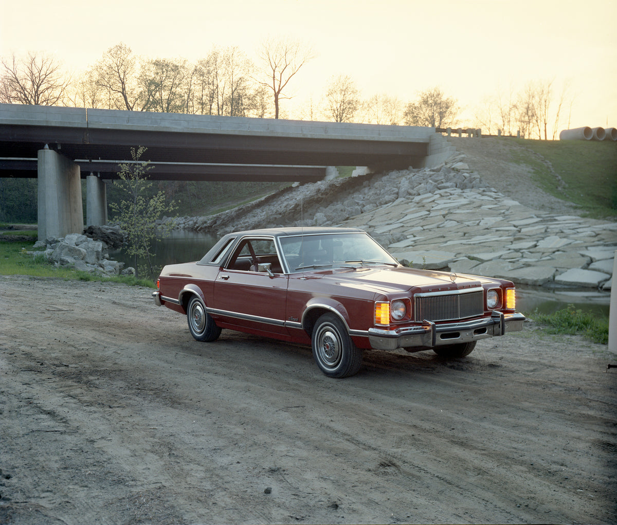 This archival image documents the 1976 Mercury Monarch two-door with Bridge in Background and is preserved in the Ford Heritage Vault as part of Ford Motor Company's historic photographic archive. Free for personal, non-commercial use. Ford Herita...