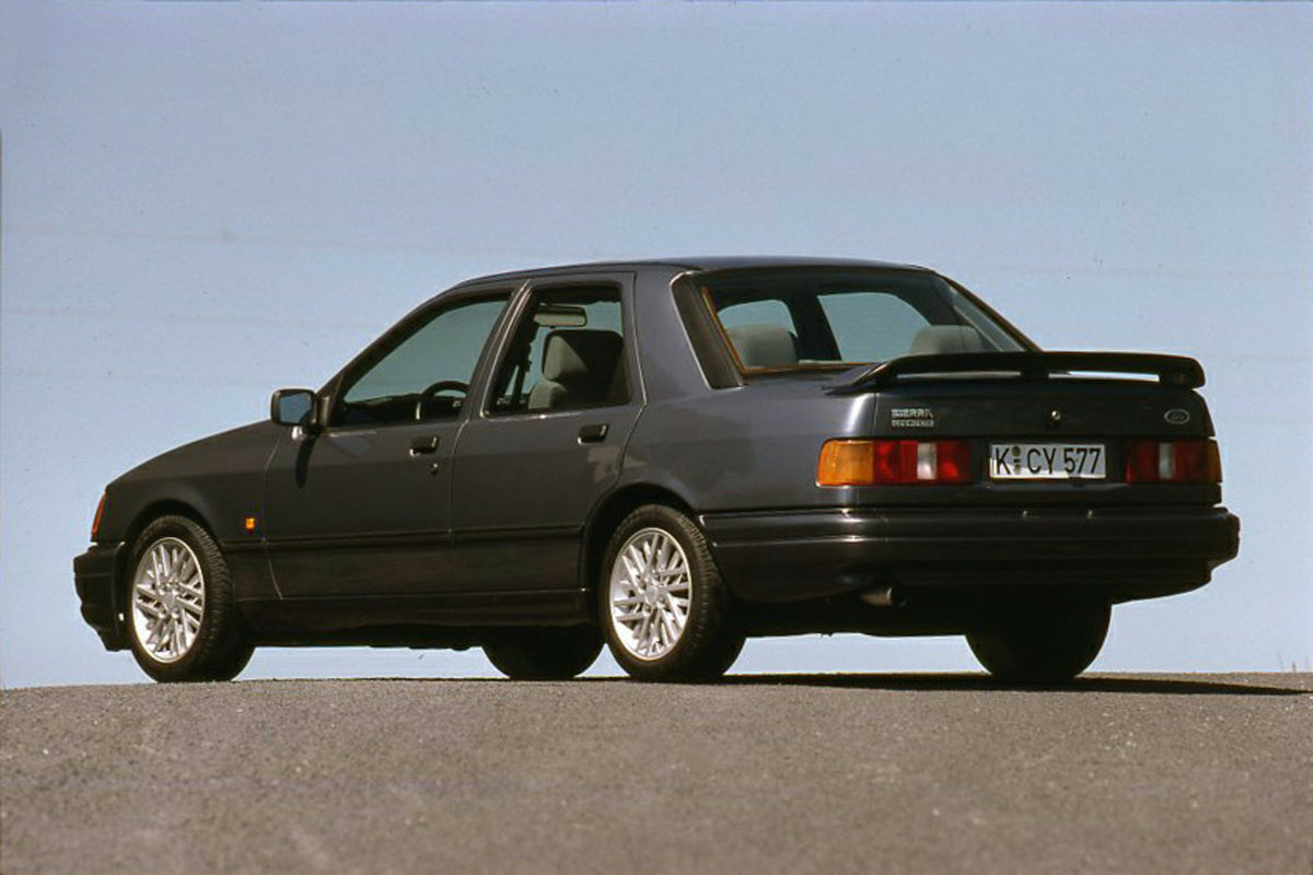 This archival image documents the 1987 Ford Sierra RS Cosworth rear view with scenic blue sky and is preserved in the Ford Heritage Vault as part of Ford Motor Company's historic photographic archive. Free for personal, non-commercial use. Ford He...