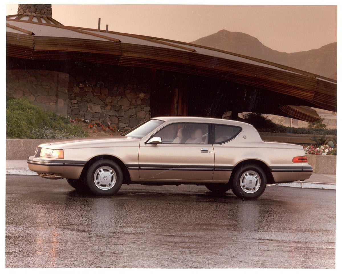 This archival image documents the 1986 Mercury Cougar side view in front of house and is preserved in the Ford Heritage Vault as part of Ford Motor Company's historic photographic archive. Free for personal, non-commercial use. Ford Heritage Vault...