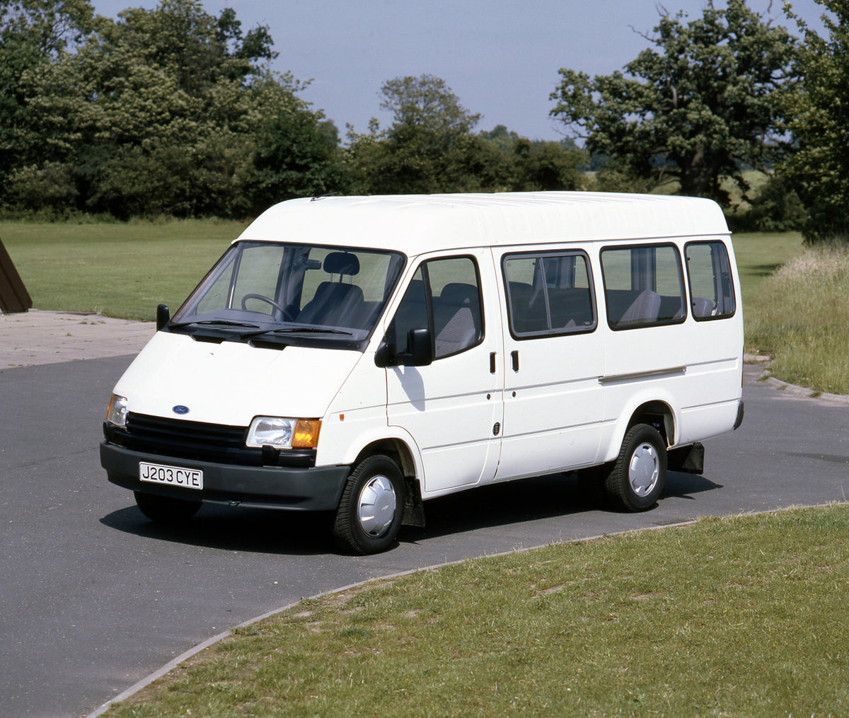 This archival image documents the 1991 Ford Transit Mark III Bus Long Wheelbase in scenic parking lot with trees and is preserved in the Ford Heritage Vault as part of Ford Motor Company's historic photographic archive. Free for personal, non-comm...