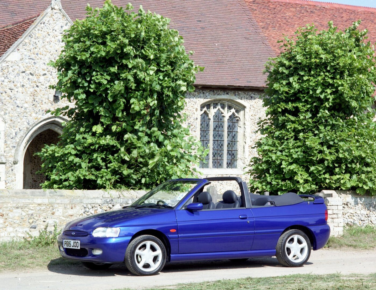 This archival image documents the 1996 Ford Escort Mark VI Cabriolet Ghia in front of scenic building and is preserved in the Ford Heritage Vault as part of Ford Motor Company's historic photographic archive. Free for personal, non-commercial use....